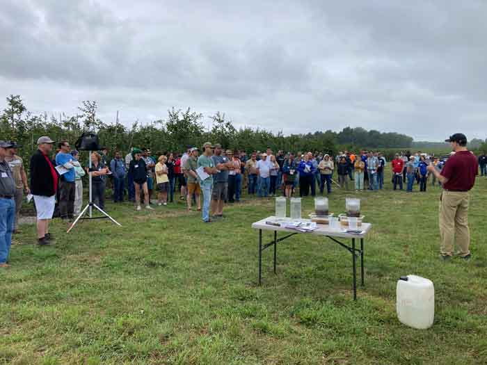 Outdoor demonstration in agricultural fieldof soil health slake tests with attendees at workshop