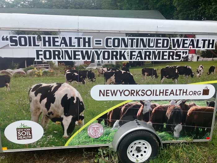 Side view of New York Soil Health trailer with background of cows in pasture.